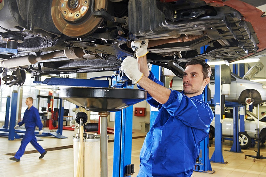 Service expert working on underside of car